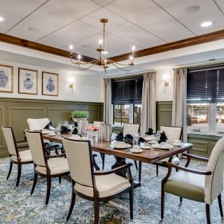 An elegantly designed dining room featuring a large table, comfortable chairs, and a modern chandelier, with artwork adorning the walls.
