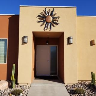 A modern house entrance featuring a decorative sun motif and cacti landscaping.