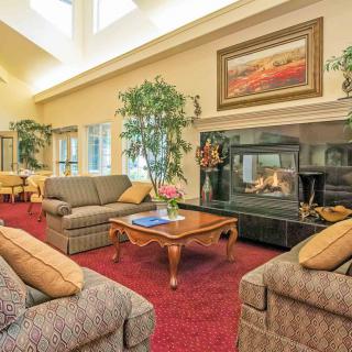 A cozy living room with plush sofas, a central coffee table, and a warm fireplace surrounded by elegant decor.