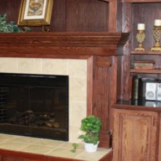 A cozy living room area with a fireplace and wooden shelves adorned with candles and a small potted plant.