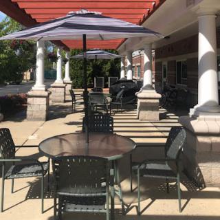 A sunny outdoor patio area with tables and chairs under colorful umbrellas.