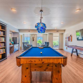 A spacious game room featuring a pool table, library shelves, and an air hockey table.