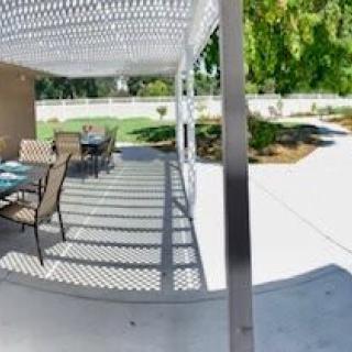 A shaded patio area with tables and chairs, set in a garden.
