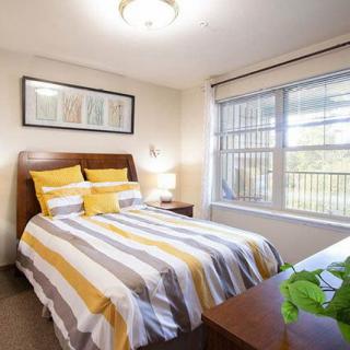 A cozy bedroom with striped bedding and natural light from a large window.