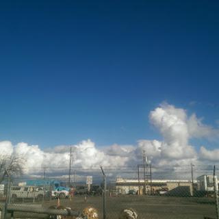 A clear blue sky with fluffy clouds.