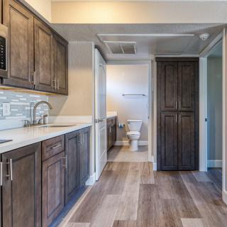 A modern kitchen with wooden cabinetry and flooring, featuring a sink and ample countertop space.