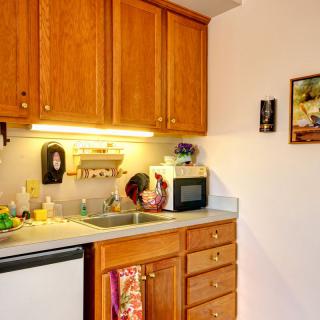 A small kitchen with wooden cabinets, a countertop, microwave, sink, and dishwasher.