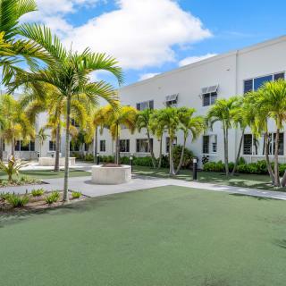 A modern building with palm trees in a courtyard under a blue sky.