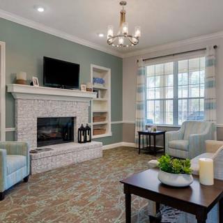 A modern living room featuring a fireplace, chandelier, and comfortable seating.