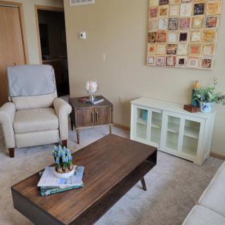 A cozy living room featuring a comfortable armchair, wooden coffee table, and modern artwork on the wall.