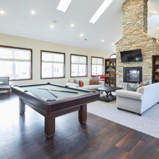 A spacious and modern living room featuring a pool table, fireplace, and comfortable seating.