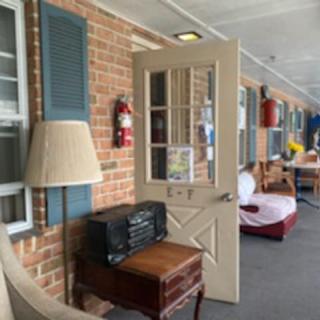 A view of a porch with a brick wall, open door, and various pieces of furniture.