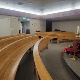 A serene interior view of a chapel featuring curved wooden benches and softly lit ambiance.