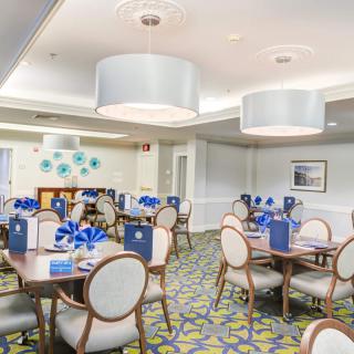 A modern restaurant dining area with neatly arranged tables and chairs, featuring stylish lighting fixtures and contemporary decor.