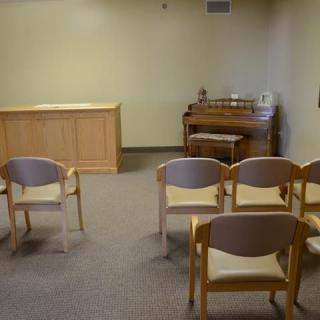 A small chapel with rows of chairs and an organ in the corner.