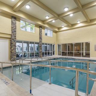 A modern indoor swimming pool with glass walls and ample lighting.