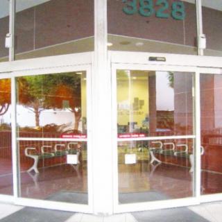 A storefront entrance with sliding glass doors, revealing empty tables inside.