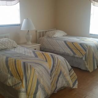 A bedroom with two twin beds, each covered with patterned blankets, and a lamp on a nightstand between them.