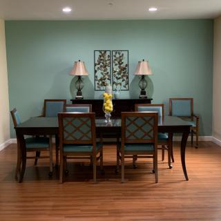 A well-decorated dining room with a large table, chairs, lamps, and wall art.