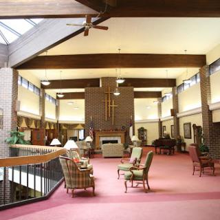 A spacious indoor lounge with comfortable seating, highlighted by natural light and wooden architectural details.