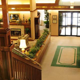 A cozy lobby interior with a wooden staircase, decorative plants, and comfortable seating.