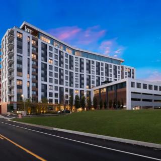 A modern residential building with a curved design against an evening sky.