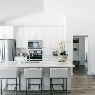 A modern, minimalist white kitchen with sleek appliances and a spacious layout.