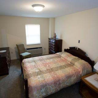 A cozy bedroom with traditional furniture and a quilt-covered bed.