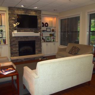 A cozy living room featuring a stone fireplace and mounted television, surrounded by comfortable seating and elegant decor.