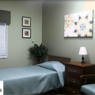A cozy and well-decorated bedroom featuring a single bed, nightstand with lamp, and decorative wall art.
