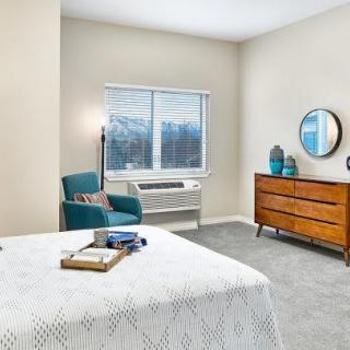 A cozy bedroom with modern furniture and a large window overlooking the outside.