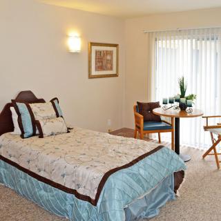 A cozy bedroom with a single bed and a small dining area.