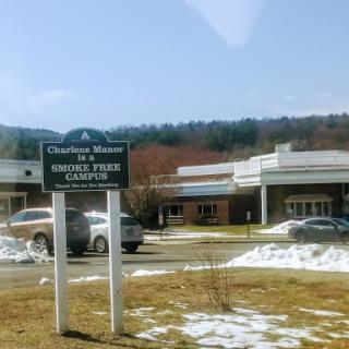 A sign for a healthcare facility with a backdrop of mountains and some lingering snow.