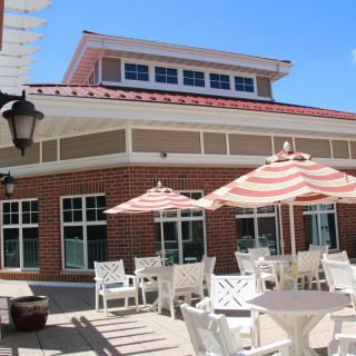 An outdoor patio with tables, chairs, and striped umbrellas on a sunny day.