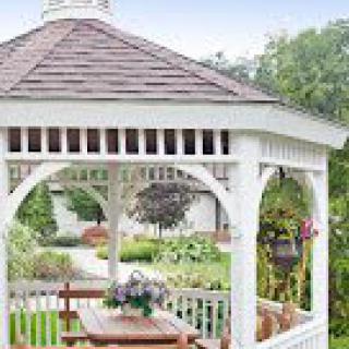 A charming wooden gazebo in a lush garden setting.
