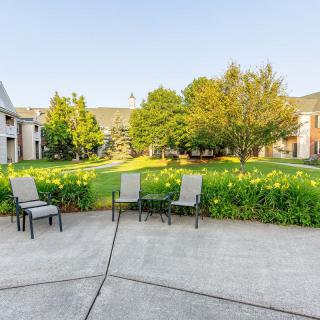 A serene outdoor patio area with chairs overlooking a lush garden and surrounding buildings.