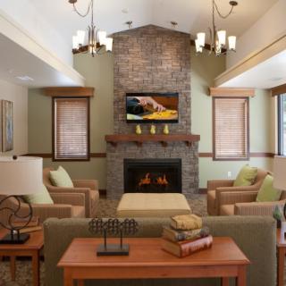 A cozy living room featuring a central fireplace, comfortable sofas, and a TV above the mantel.