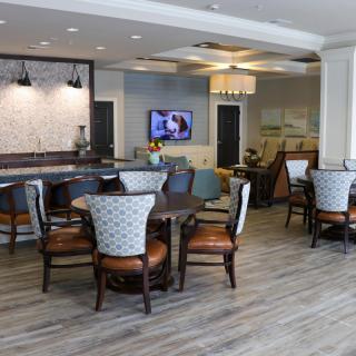 A modern lounge area with tables and chairs, featuring a television and stylish decor.