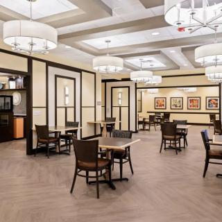 A spacious and elegantly decorated dining area with multiple tables and modern chandeliers.