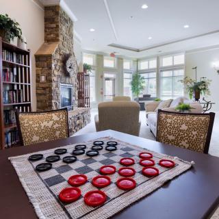 A cozy living room with a checkers game set up on a wooden table, surrounded by modern furniture and natural lighting.