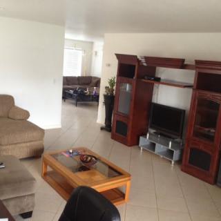 A cozy living room featuring a sectional sofa, wooden entertainment center, and a glass coffee table.