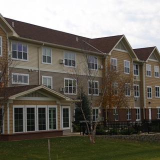 A multi-story residential building with a landscaped front lawn.