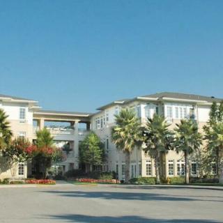 A residential apartment building surrounded by palm trees under a clear blue sky.