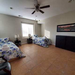 A spacious bedroom with twin beds and a ceiling fan.