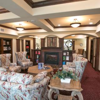 A cozy lounge area with comfortable seating and a fireplace, surrounded by bookshelves.