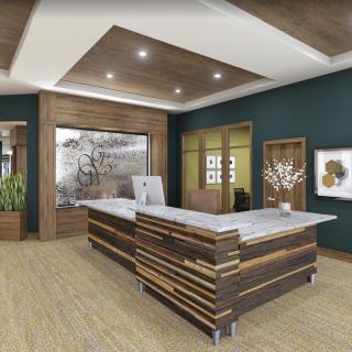 A modern office lobby featuring a stylish reception desk with wood accents and surrounding artwork.