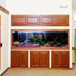 A large aquarium built into wooden cabinetry in a living room setting.