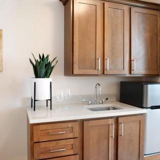 A modern kitchen setup featuring wooden cabinets, a small sink, and a mini fridge.
