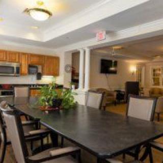 A spacious dining area connected to a kitchen, featuring a large table and comfortable chairs.