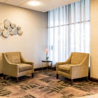 A cozy lobby area with two armchairs, a small table, and decorative artwork on the wall.